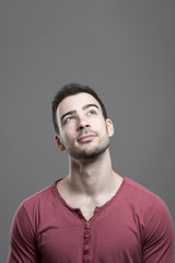 Obraz premium Concept of handsome young man looking up having an idea with empty copy space over gray studio background.