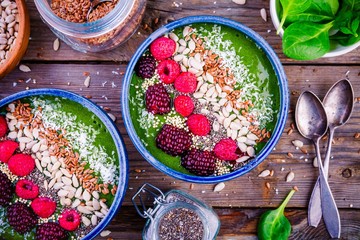 Green spinach smoothie bowl with raspberry,.blackberry,.flax seeds, sunflower seeds and coconut...