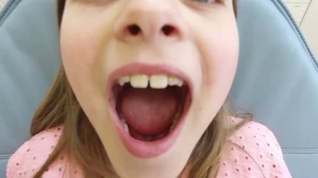 Close up of cute little girl at dentist, looking at camera and smiling