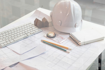 Structural engineer and architect desk with safety helmet, blueprint and model house, double...