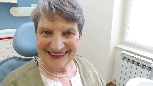Close up of elderly woman holding smartphone with photo of dental X- ray at dentist