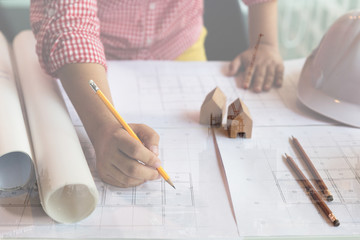 Architect or engineer working with blueprints in office, Construction concept. double exposure with crane and building under construction