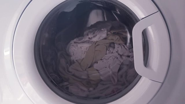Washing machine with dirty clothes inside, front cover of household equipment