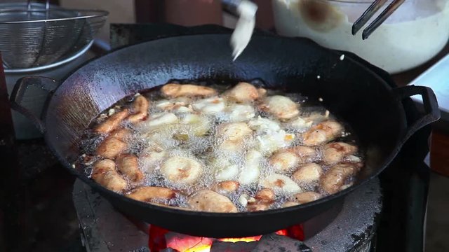 Fried cakes cooking into oil pan on the street