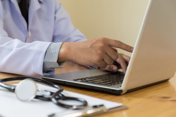 Doctor showing medical records on his computer, he is pointing at the screen in clinic