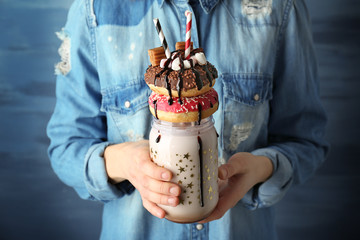 Girl holding milkshake with donuts and other sweets in jar