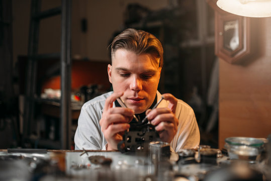 Watchmaker holding with tweezers a gear of hours