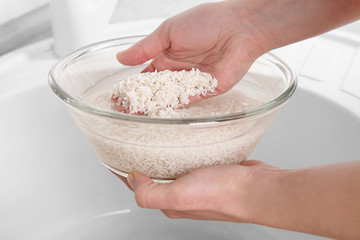 Woman rinsing rice in glass bowl with water