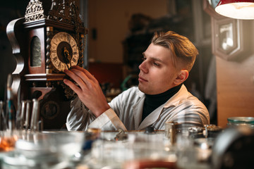 Watchmaker adjusts the mechanism of old wall clock