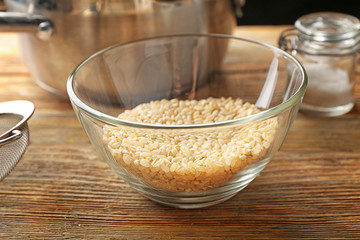 Glass bowl with brown short grain rice on wooden table