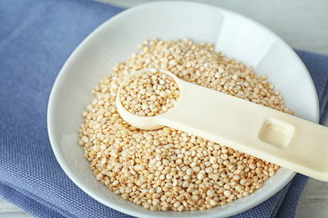 Organic quinoa seeds and scoop in bowl, closeup