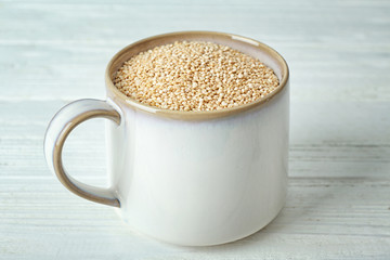 Organic quinoa seeds in mug on wooden background
