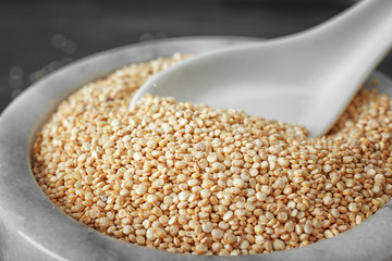 Organic quinoa seeds and spoon in bowl, closeup