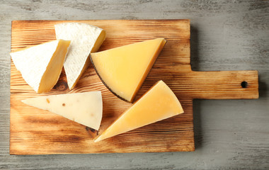 Board with delicious cheese on wooden table