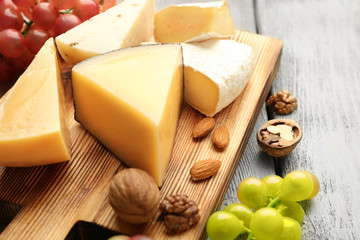 Delicious cheese, grape and nuts on wooden board