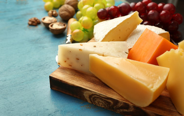 Cheeseboard, grape and nuts on blue textured background