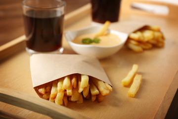 Tray with tasty fries, cheese sauce and glasses of soda water, closeup