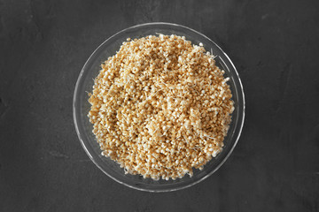 Top view of glass plate with sprouted organic white quinoa grains on dark background