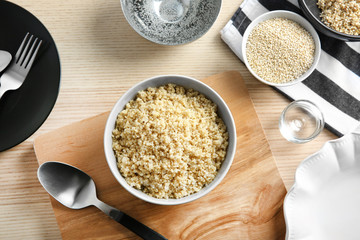 Ceramic bowl with boiled sprouted organic white quinoa grains on kitchen wooden table