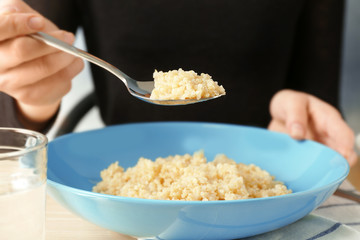 Woman eating quinoa porridge at kitchen table
