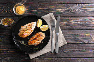 Plate with delicious chicken breasts and  lime on table