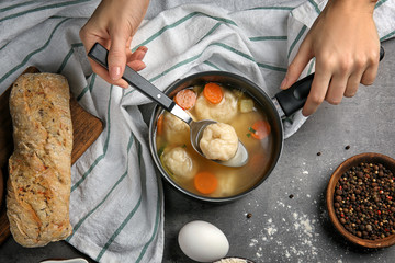 Female hands holding stewpan with delicious chicken and dumplings on kitchen table