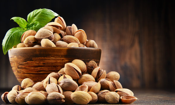 Bowl with pistachio on wooden table