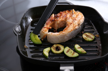 Cooking salmon steak and zucchini on grill pan