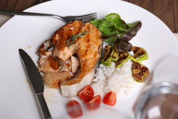 Plate with grilled salmon steak, vegetables and rice on dinning table