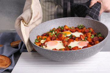 Woman holding pan with baked eggs, closeup
