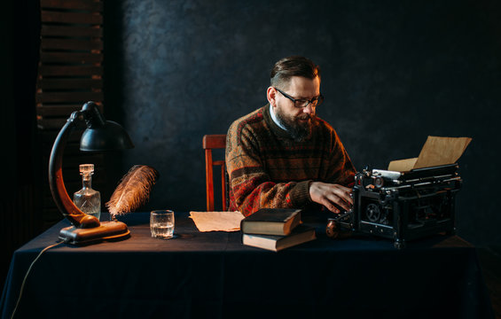 Writer in glasses typing on vintage typewriter
