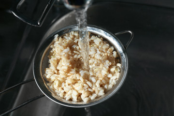 Washing brown rice with water in sieve