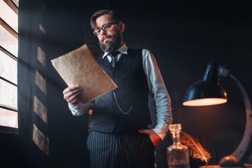 Bearded writer in glasses reads handwritten text