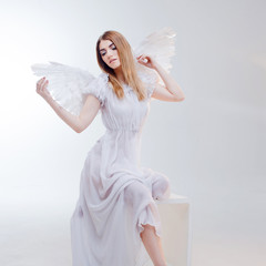 Young, wonderful blonde girl in the image of an angel with white wings.