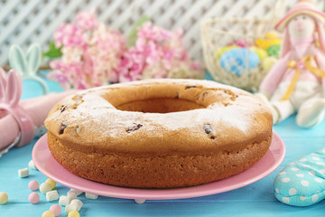 Pink plate with delicious Easter cake on blue background