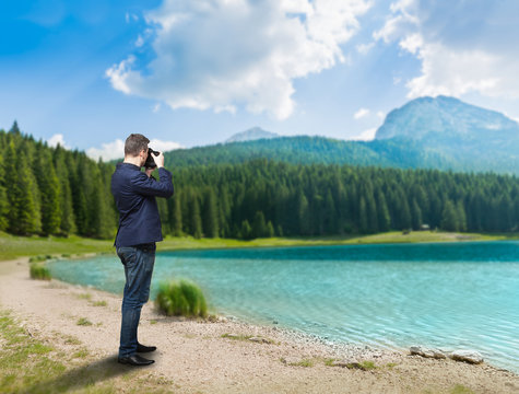 Male photographer taking picture of lake on camera