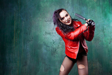 Aggressive punk woman strike someone with a bat, in red leather jacket