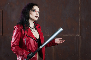 Aggressive punk woman with a bat, in red leather jacket