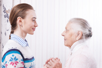 Helping hands, care for the elderly concept. Senior and caregiver holding hands at home.