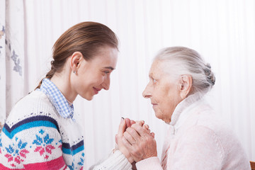 Senior and caregiver holding hands at home