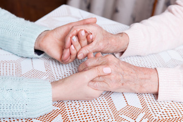 Senior and young holding hands at home