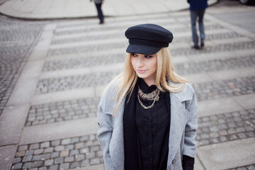 Fototapeta premium Young, hip and attractive blonde walking around the city, girl in a stylish hat and a gray coat. Pedestrian crossing