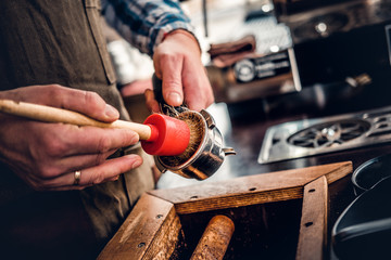 A man cleans coffee machine with a tassel.