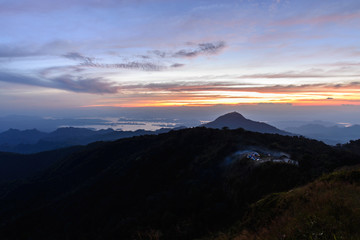 Campfire smoke from camping site at beatiful place, mountain peak at sunnset.