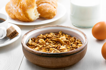 Delicious healthy breakfast with oatmeal granola, coffee and croissant on a white wooden table. Traditional healthy food. Close-up