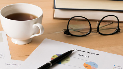 Work desk with bussiness chart  and spectacles on wooden desk.