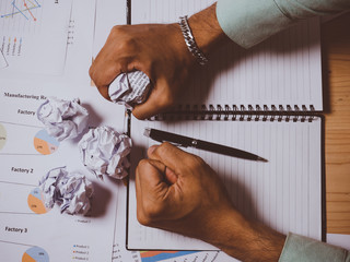 Businessman with crumpled paper ball on wooden table.