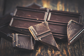 dark chocolate over wooden backround with some cocoa powder