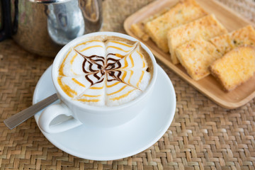 Cappuccino cup with crispy butter toast on weaving a mat