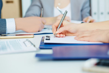 Business woman making notes at office workplace with colleague on the background. Business job offer, financial success, certified public accountant concept.